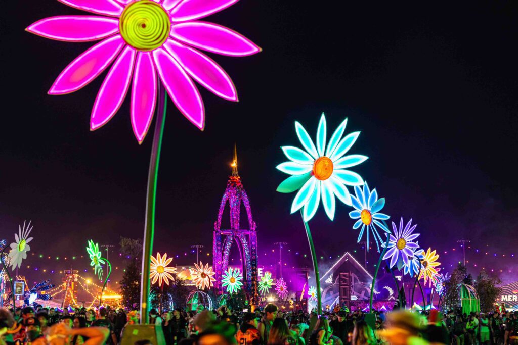 Neon daisies light up the main street as festivalgoers walk by